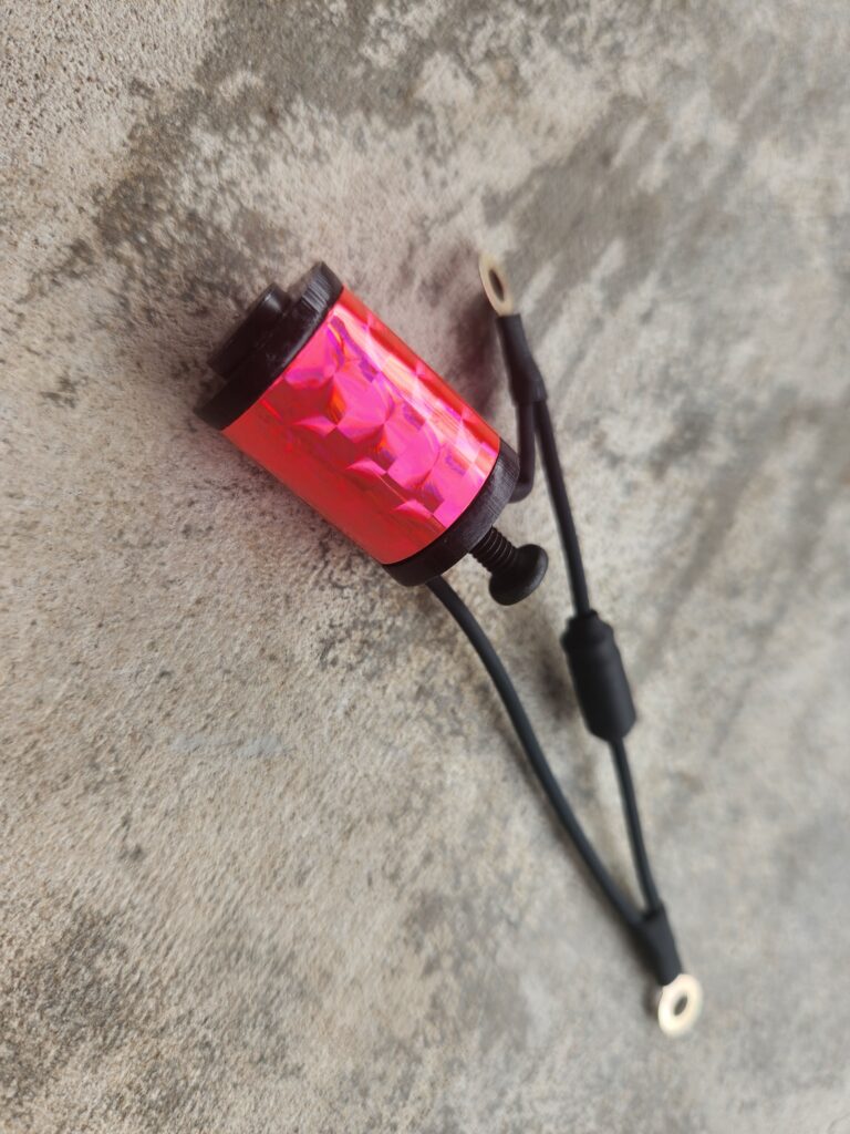 A pink and black tattoo machine lying on a concrete surface.