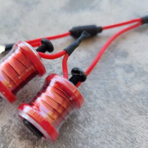 Close-up of red wired earphones on a textured surface.