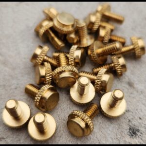 Close-up of small brass screws scattered on a surface.
