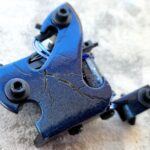 Close-up of a cracked blue metal component with bolts.