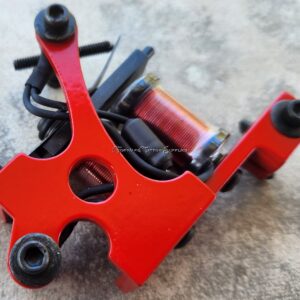 Close-up of a red tattoo machine on a gray surface.