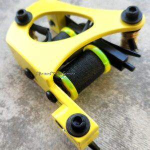 Close-up of a yellow tattoo machine with black coils.