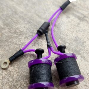 Close-up of purple coil ignition wires with black connectors on a gray surface.