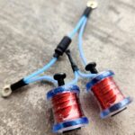 Two small blue coils wrapped with red wire connected by blue wires.