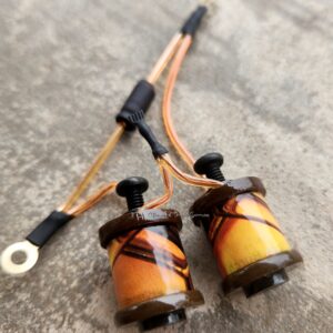 Close-up of two copper coil inductors with black connectors on a gray surface.