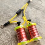 Close-up of a fishing line spooler with red fishing lines and yellow cords.
