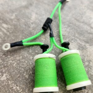 Green thread spools connected by green wires on a gray surface.