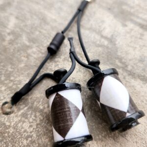 Two black and white geometric patterned ceramic pendants on cords.
