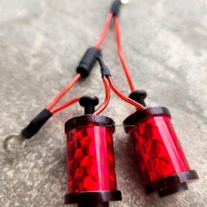 Close-up of two red cylindrical electronic components connected by black and red wires.