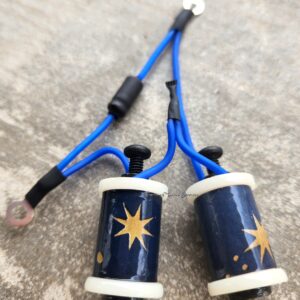A pair of blue and white candles with star designs connected by blue cords.