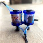 Two small blue containers with liquids connected by tubes on a wooden surface.