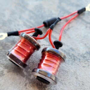 Close-up of two red coil inductors with wires on a gray surface.
