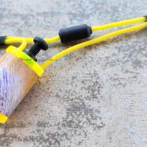 Close-up of a yellow slingshot on a textured surface.