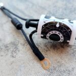 Close-up of an electrical cable with a ring terminal on a concrete surface.