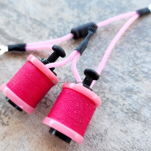Close-up of pink earbuds with black and white accents on a textured surface.