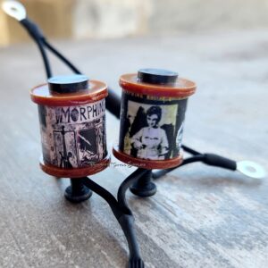 Two small decorative figurines made from film reels with attached legs and spoons.