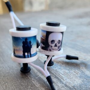 Two tattoo machines with custom skull and couple designs.