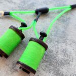 Close-up of green thread spools on a gray surface.