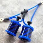 Close-up of blue cylindrical components with wires on a textured surface.