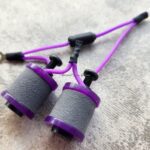 Close-up of purple and gray hand grip strengtheners on a textured surface.