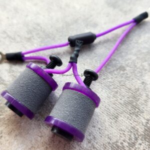 Close-up of purple and gray hand grip strengtheners on a textured surface.