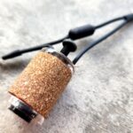 Close-up of a fishing rod handle with cork grip on a textured surface.