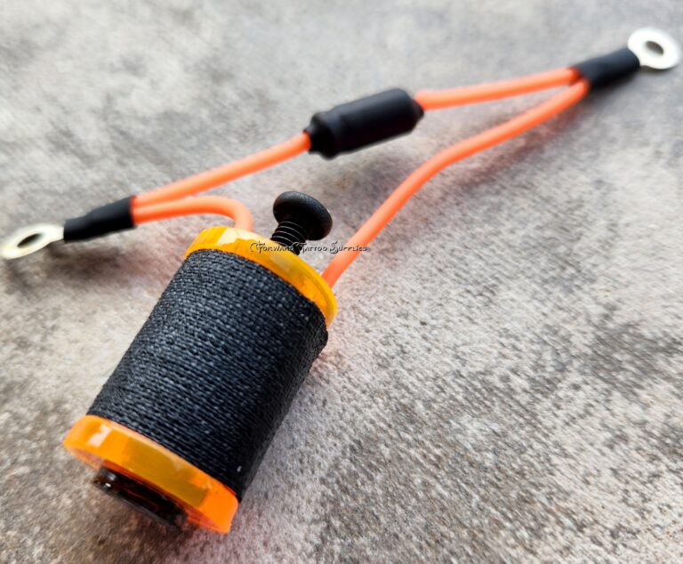 Close-up of a black and orange fishing line spool on a textured surface.