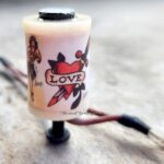 A tattoo machine with a love-themed design on its grip.