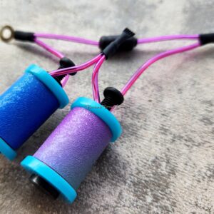 Two colorful yo-yos with purple strings resting on a textured surface.