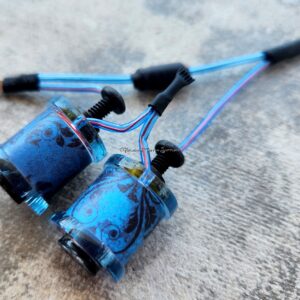 Close-up of two blue fishing reels on a concrete surface.