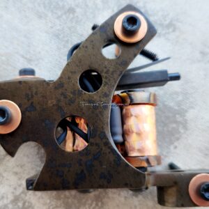 Close-up of a rusty tattoo machine with copper coils.