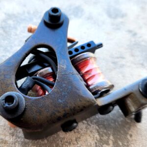 Close-up of a tattoo machine with a red spring coil.