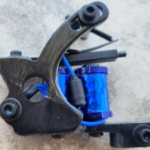 Close-up of a tattoo machine with a blue coil.