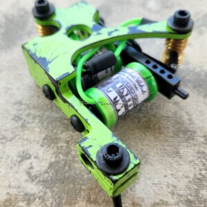 Green tattoo machine on textured surface.