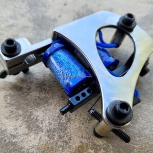 Tattoo machine with blue coils on surface.