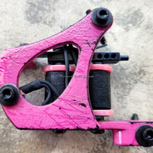 Pink tattoo machine on textured surface.