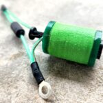 Green-wrapped coil with wires and ring terminal