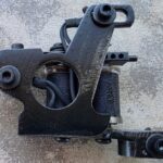 Black tattoo machine with textured surface design.