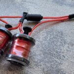 Red tattoo machine coils with black connectors.