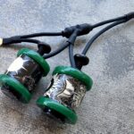 Green tattoo machine coils with intricate designs.