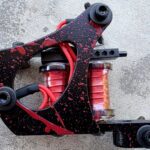 Black tattoo machine with red splatter details.