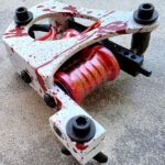 Tattoo machine with red splatter design details.