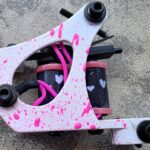 Pink splatter tattoo machine with heart motifs.