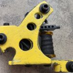 Yellow tattoo machine with black coil design.