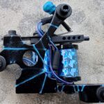 Tattoo machine with blue accents and wires.