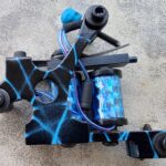 Black tattoo machine with blue lightning design.