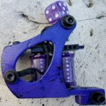 Purple tattoo machine with dice on top.