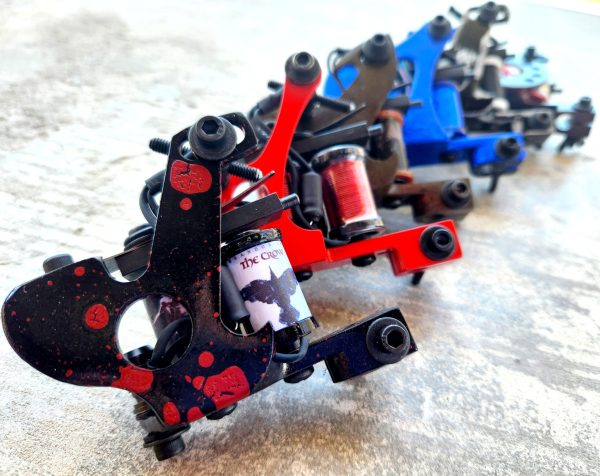 Close-up of colorful tattoo machines arranged in a row.